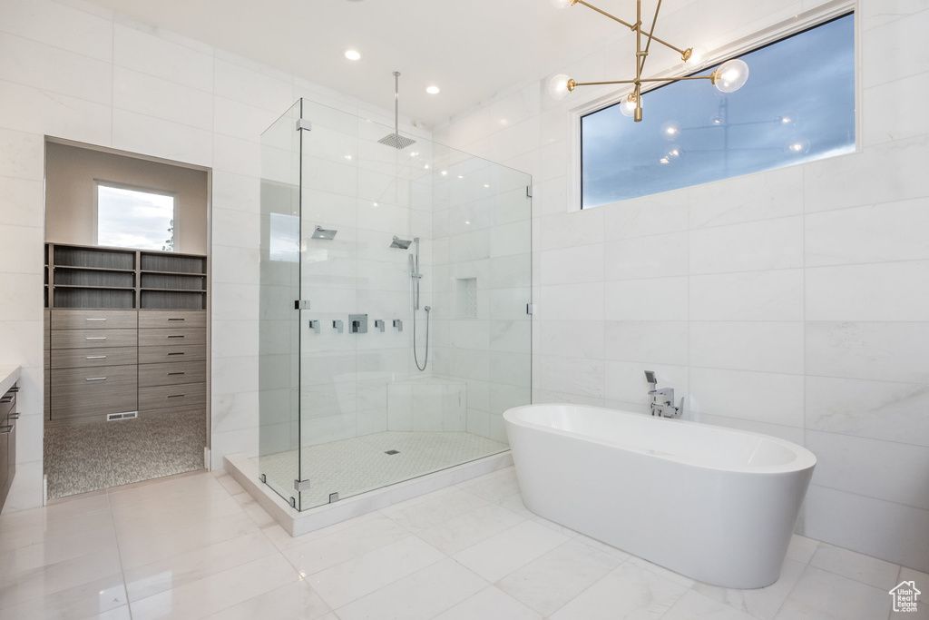 Bathroom featuring tile walls, healthy amount of natural light, a stall shower, a soaking tub, and tile patterned floors