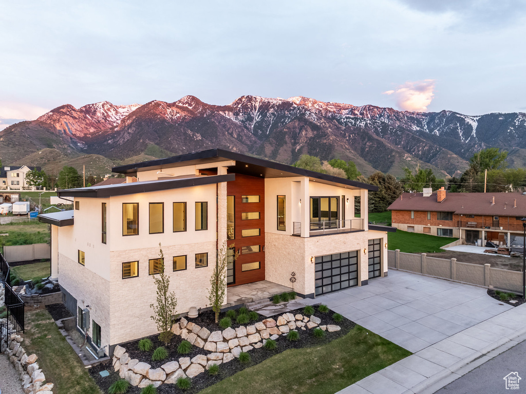 Contemporary house with concrete driveway, a mountain view, fence, a balcony, and a garage