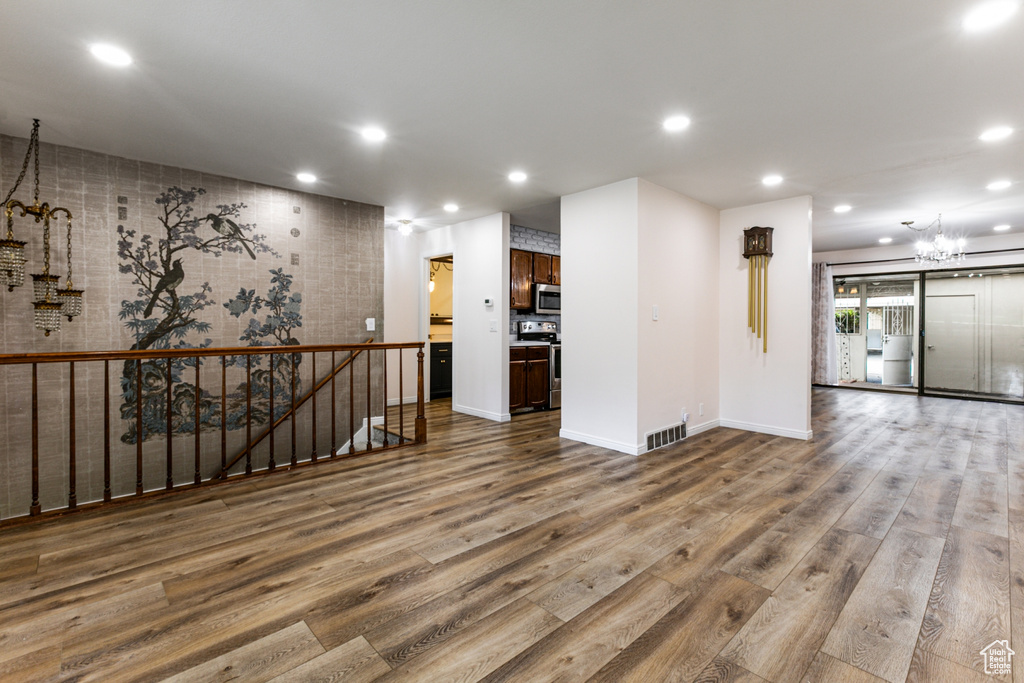 Spare room with a chandelier, wood finished floors, recessed lighting, and baseboards