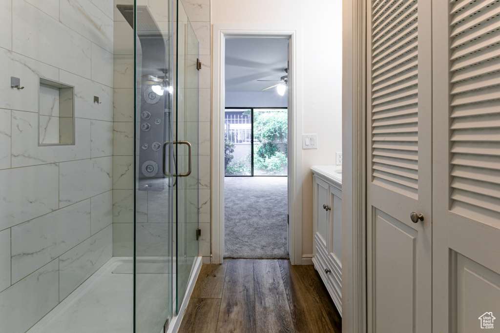 Bathroom featuring ceiling fan, wood finished floors, a shower stall, and vanity