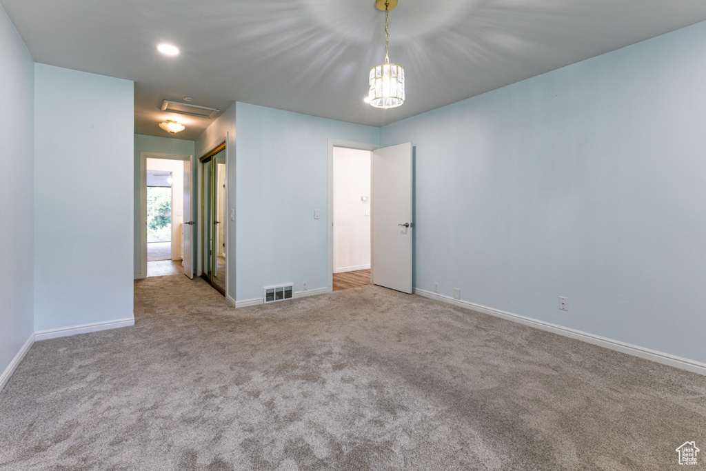 Spare room with carpet floors, baseboards, and a chandelier