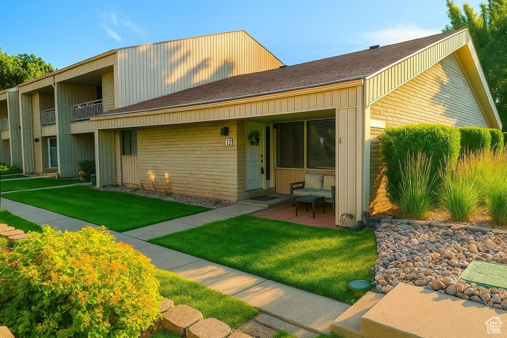 Multi unit property featuring brick siding, a front lawn, and a shingled roof