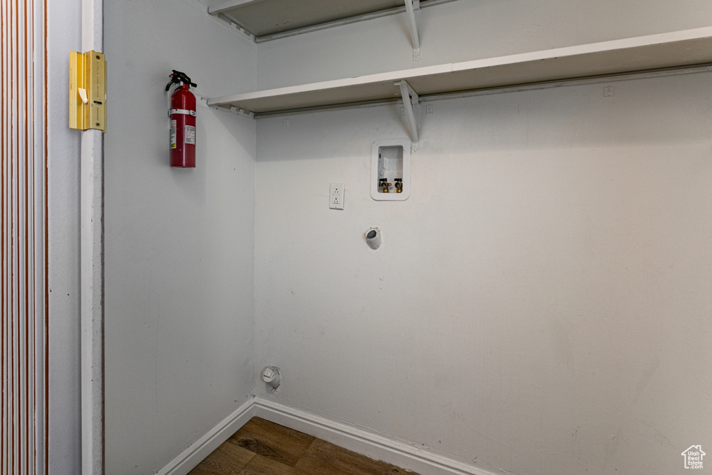 Clothes washing area with baseboards, washer hookup, and dark wood-type flooring