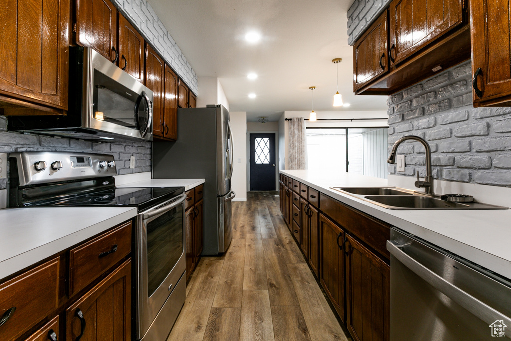 Kitchen with stainless steel appliances, a sink, light countertops, dark wood-style flooring, and recessed lighting
