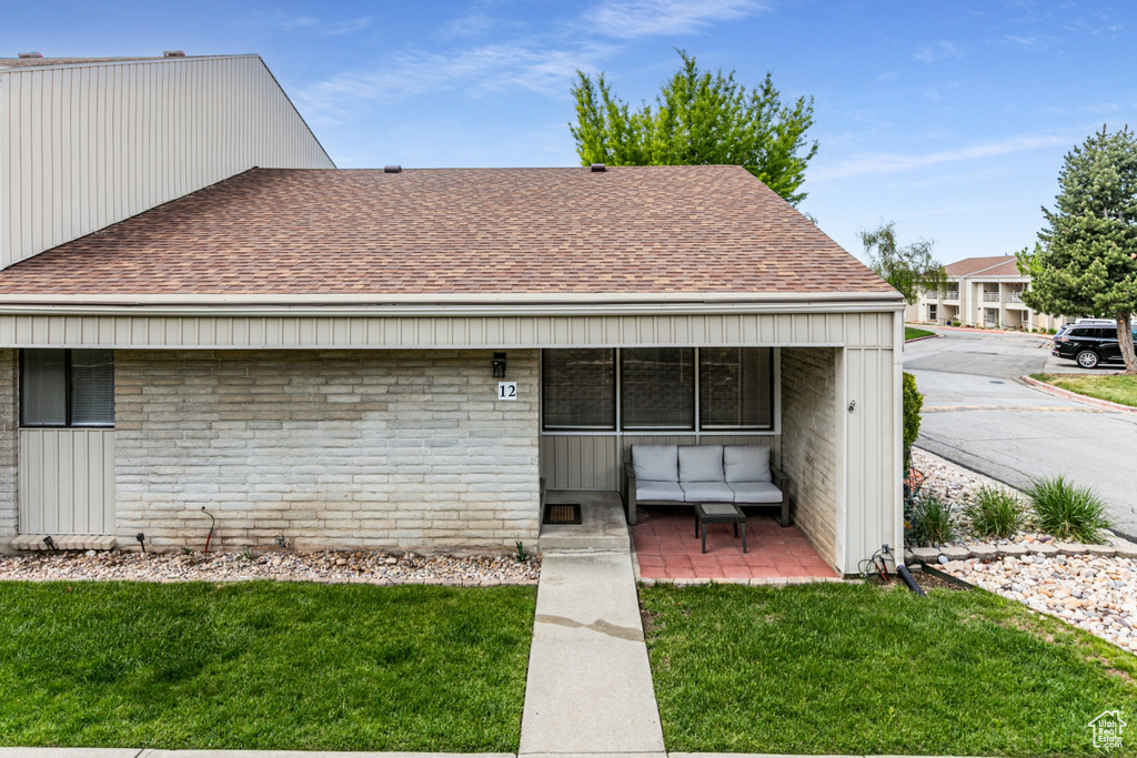 View of front of house with a shingled roof and a front lawn