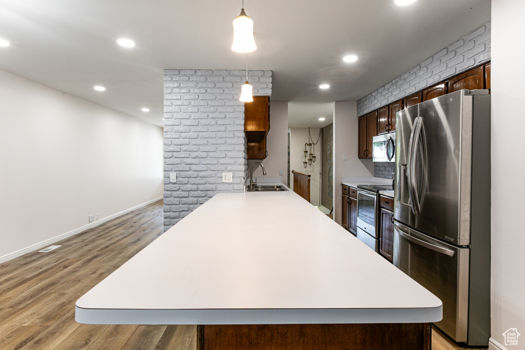 Kitchen featuring stainless steel appliances, a sink, light countertops, light wood-type flooring, and recessed lighting