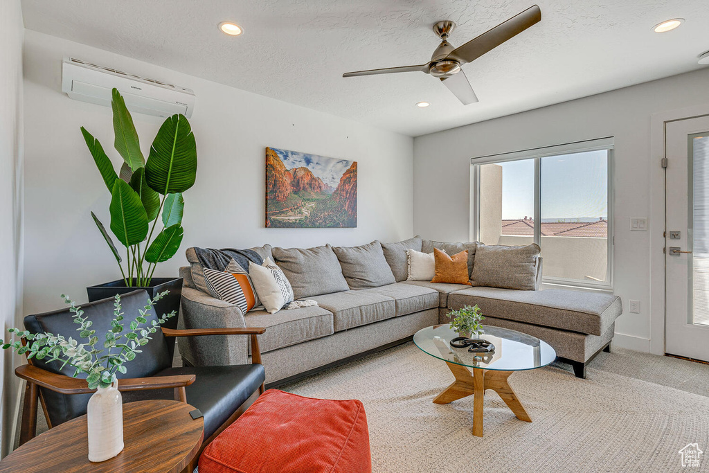 Carpeted living area featuring a wall mounted air conditioner, ceiling fan, and recessed lighting