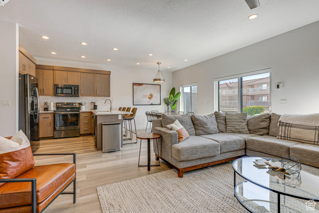 Living area with light wood-type flooring and recessed lighting