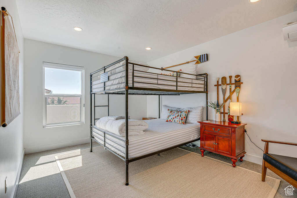 Bedroom featuring baseboards, light colored carpet, recessed lighting, and an AC wall unit