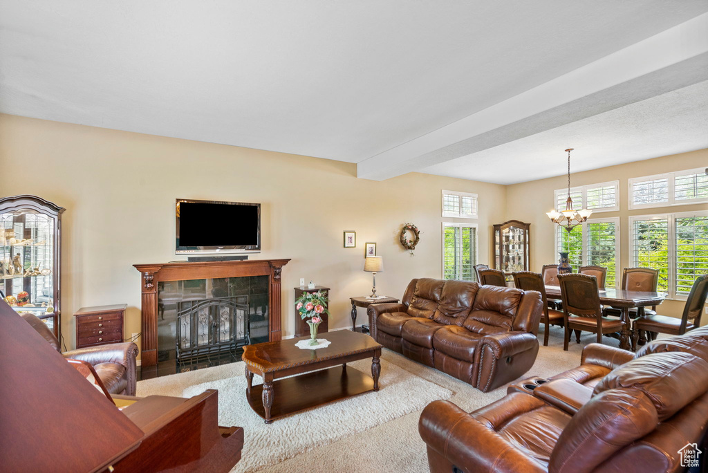 Carpeted living area with a tile fireplace, a chandelier, and beam ceiling