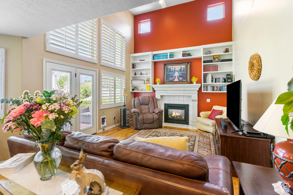 Living area with a high ceiling, a tile fireplace, and wood finished floors