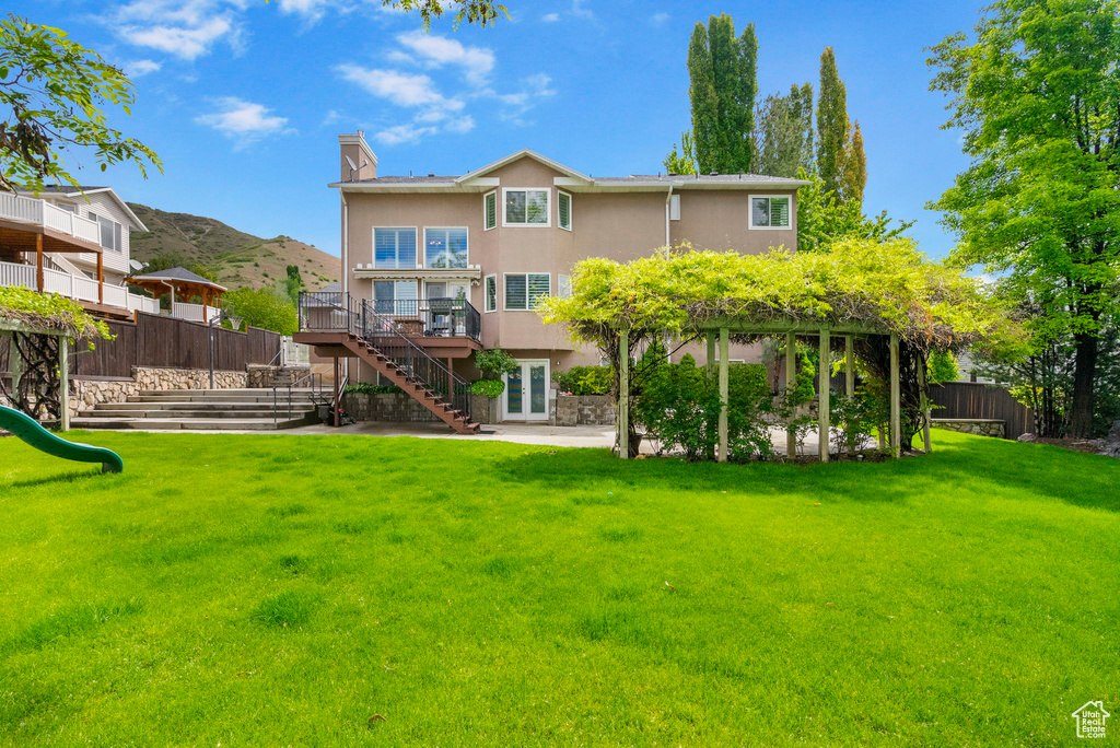 Rear view of house with stairway, a playground, a deck, stucco siding, and a patio area