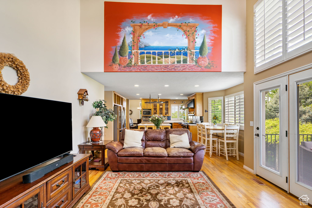 Living room featuring a towering ceiling, light wood-style floors, and recessed lighting