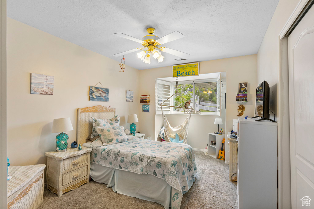Bedroom featuring light carpet, a ceiling fan, a textured ceiling, and baseboards