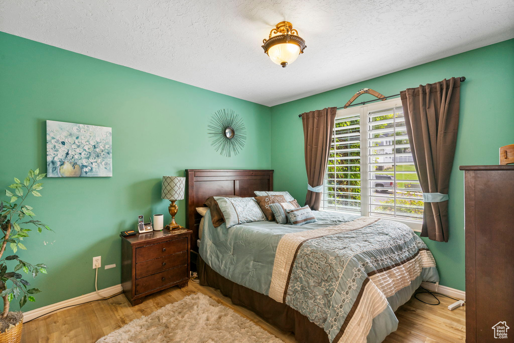 Bedroom with baseboards, wood finished floors, and a textured ceiling