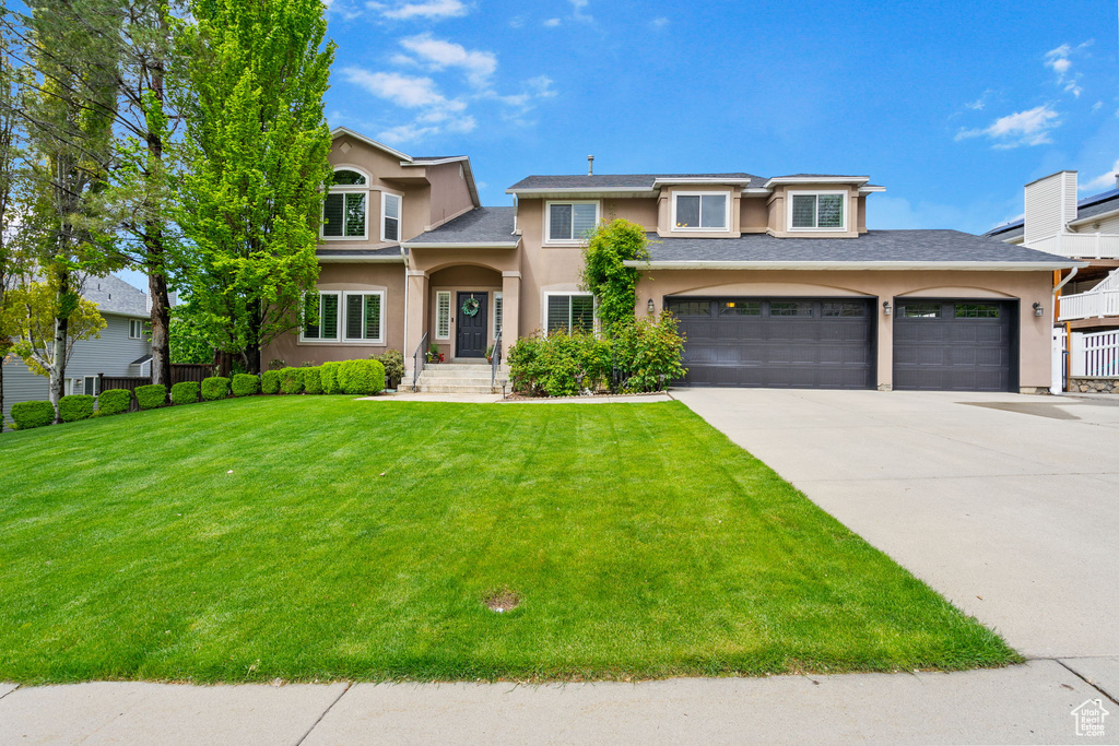 View of front of property with stucco siding, concrete driveway, and a front lawn