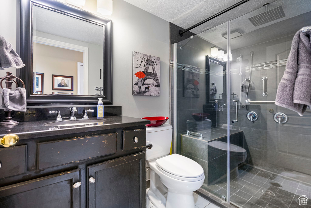 Full bath with toilet, vanity, tile patterned floors, a shower stall, and a textured ceiling