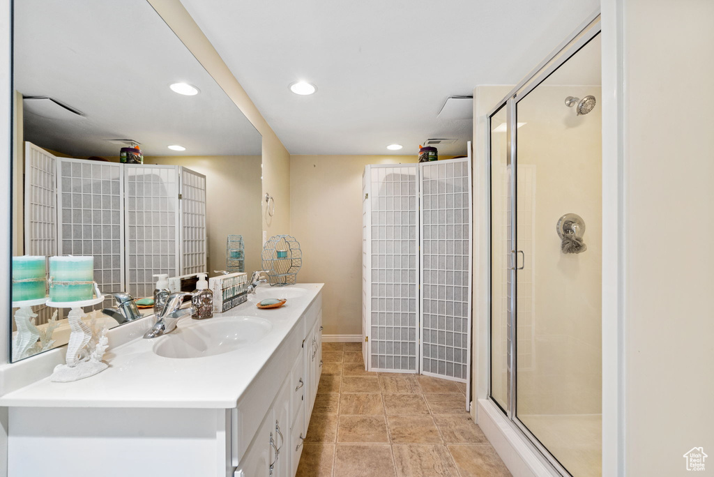 Full bathroom with a stall shower, double vanity, recessed lighting, and baseboards