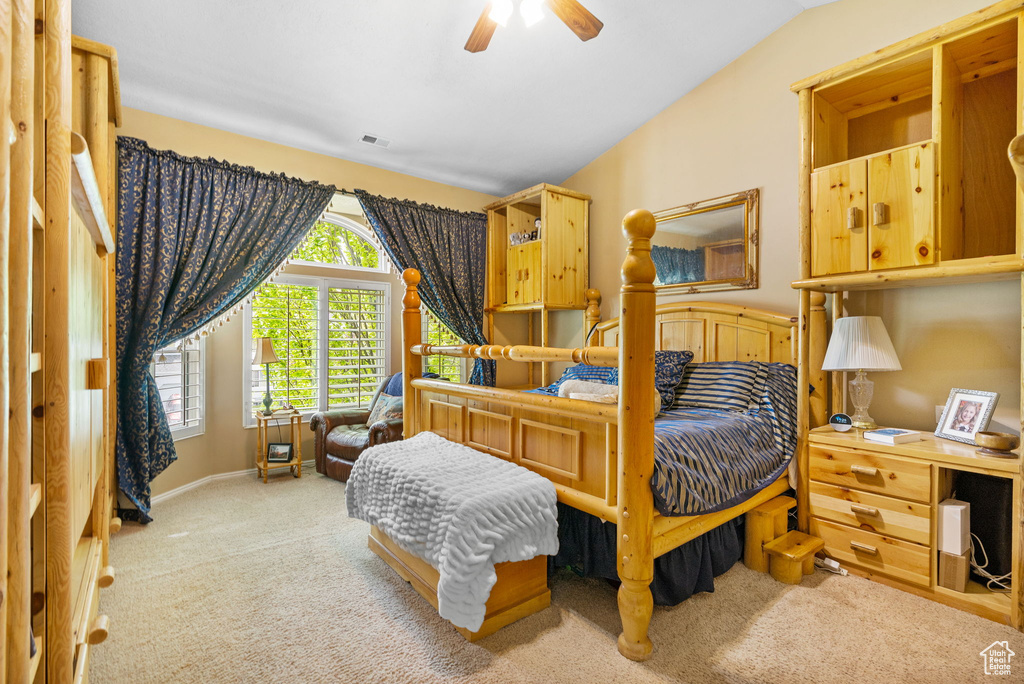 Carpeted bedroom featuring lofted ceiling and a ceiling fan