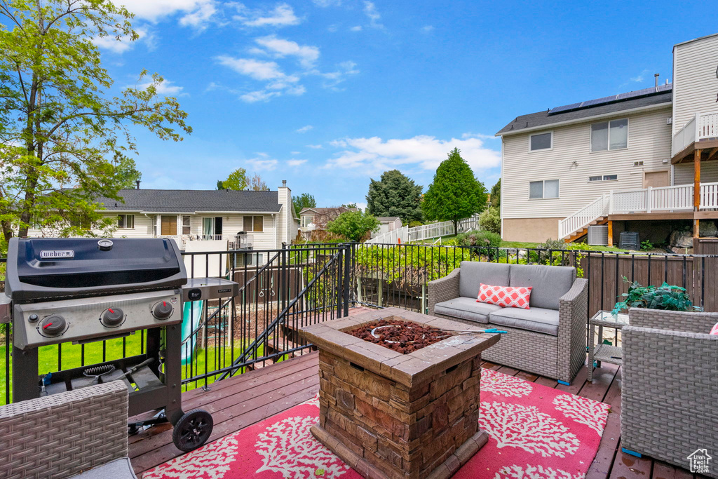Wooden terrace featuring an outdoor living space with a fire pit, a fenced backyard, a residential view, and a grill