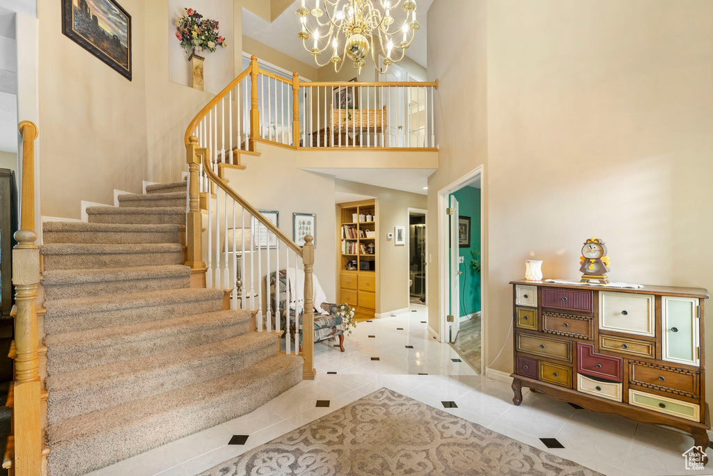 Stairway featuring tile patterned floors, a chandelier, baseboards, and a towering ceiling