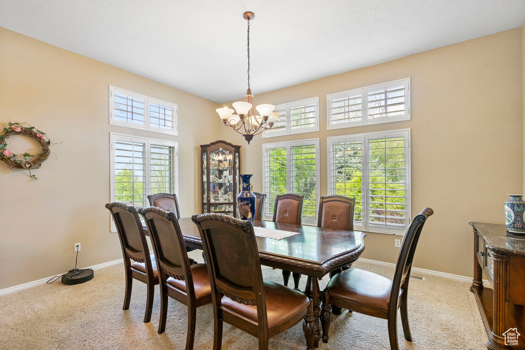 Dining space featuring a chandelier, baseboards, and light carpet