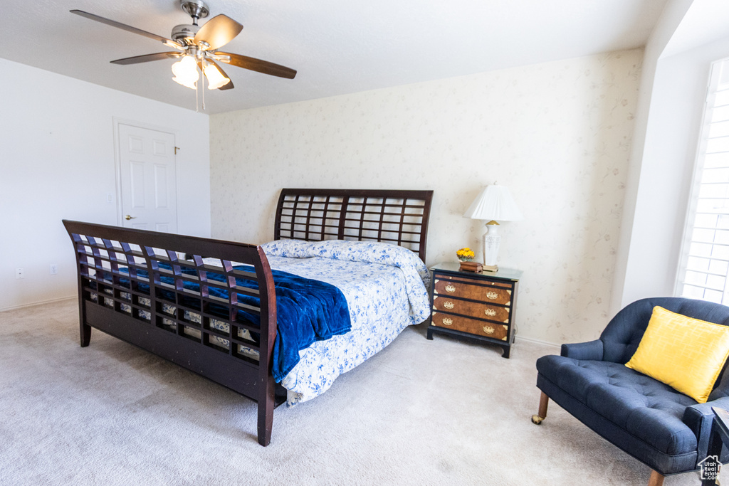 Carpeted bedroom featuring wallpapered walls, ceiling fan, and baseboards