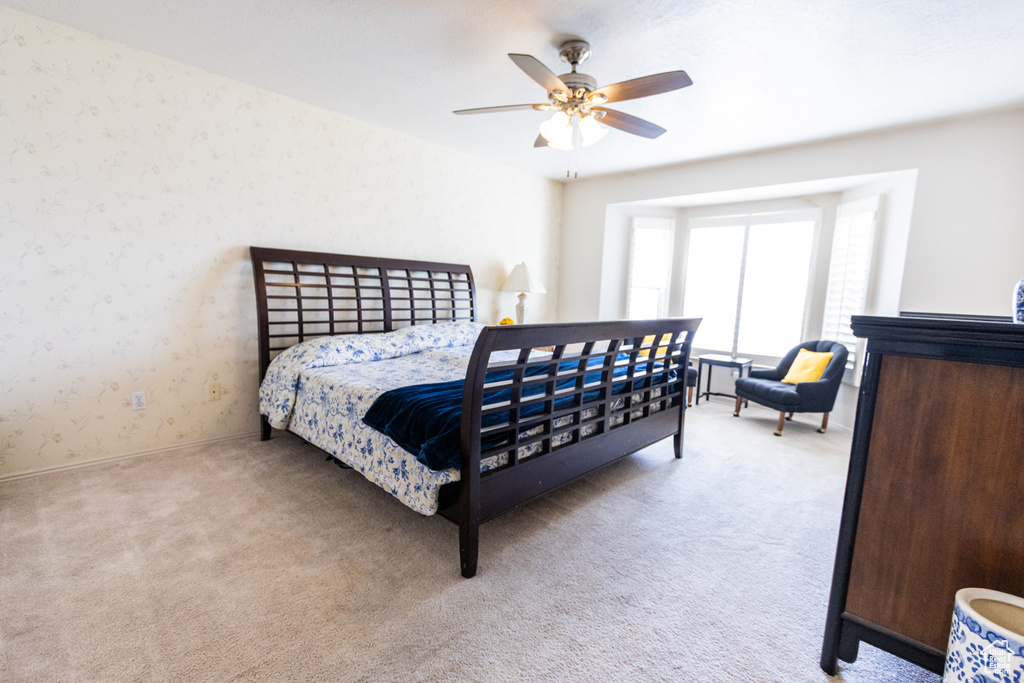 Carpeted bedroom featuring wallpapered walls, ceiling fan, and baseboards