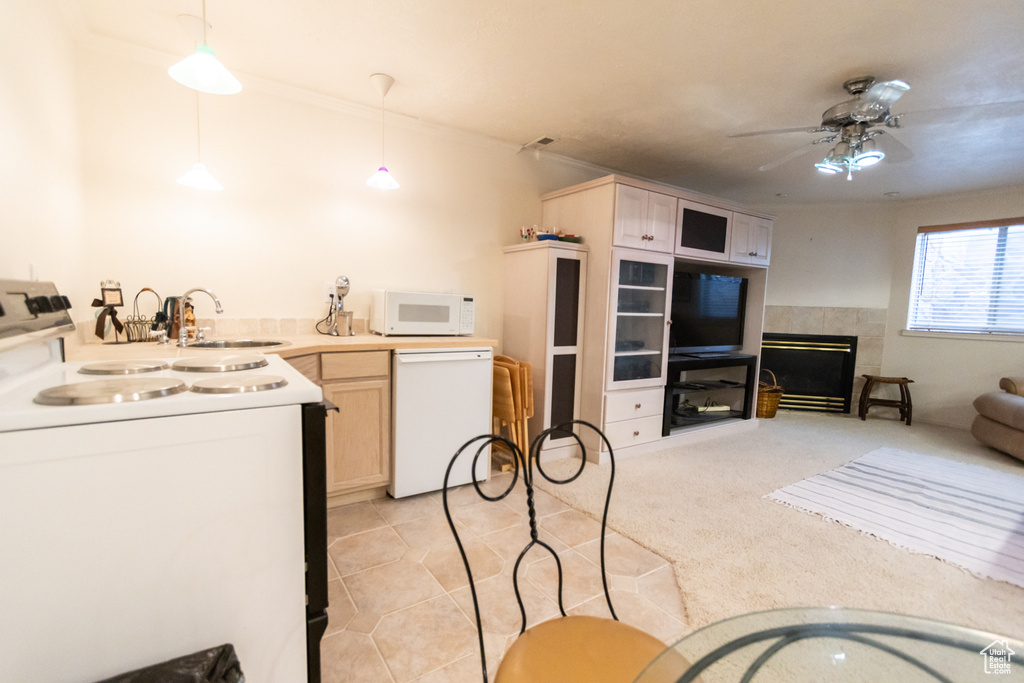 Kitchen with white appliances, a sink, ceiling fan, a tile fireplace, and pendant lighting