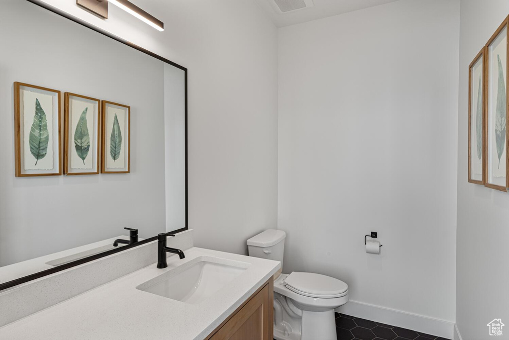 Half bathroom featuring tile patterned flooring, toilet, vanity, and baseboards