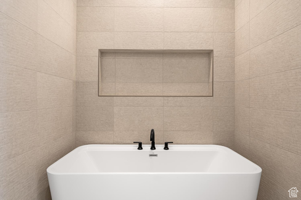 Full bath featuring a freestanding bath and tile walls