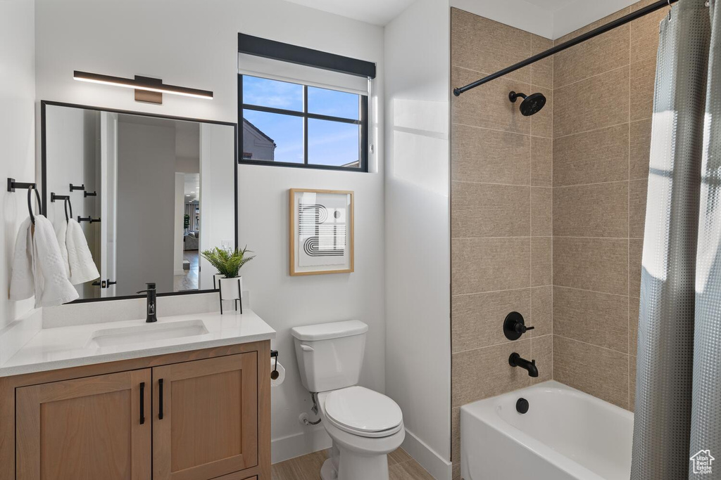 Bathroom featuring toilet, shower / tub combo, vanity, and baseboards