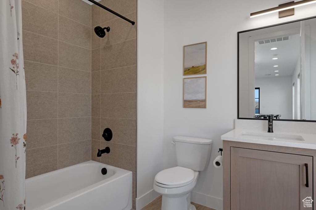 Bathroom with vanity, toilet, tub / shower combination, and baseboards