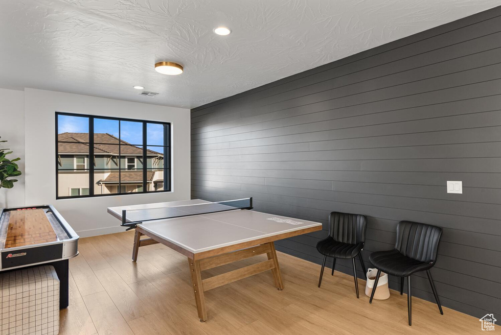 Recreation room with light wood-type flooring, recessed lighting, a textured ceiling, and baseboards