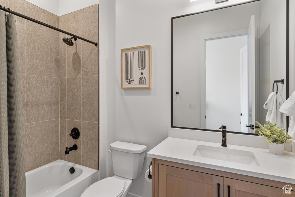 Full bathroom featuring toilet, shower / tub combo with curtain, and vanity