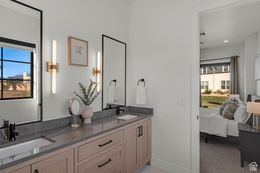 Bathroom with baseboards, double vanity, and ensuite bathroom