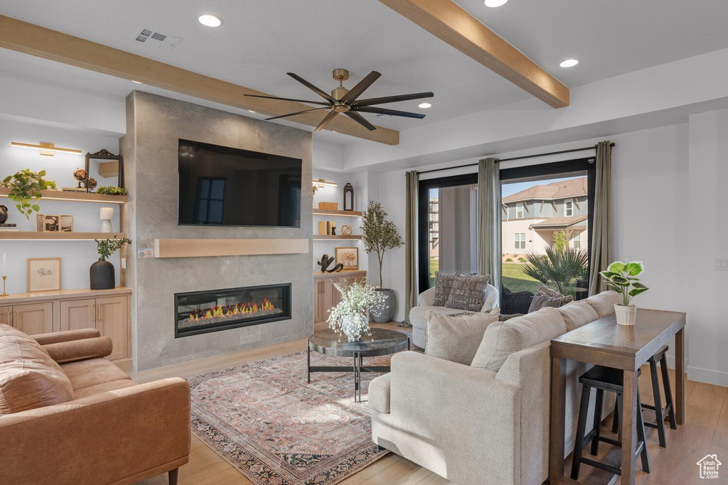 Living area featuring a fireplace, wood finished floors, a ceiling fan, beam ceiling, and recessed lighting