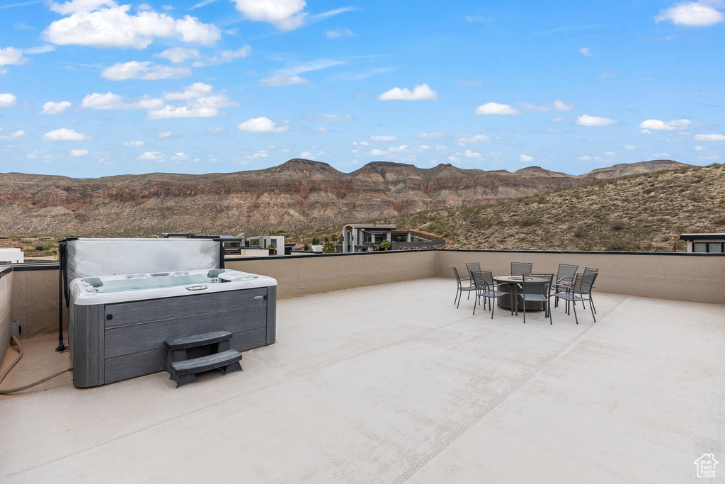 View of patio with a mountain view, a hot tub, and outdoor dining area