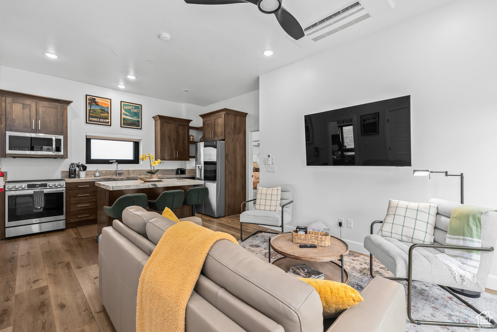 Living area with a ceiling fan, light wood-style floors, and recessed lighting