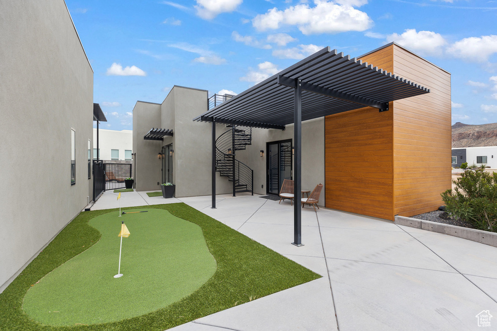 Surrounding community featuring an area to practice putting, a pergola, a patio, a mountain view, and fence