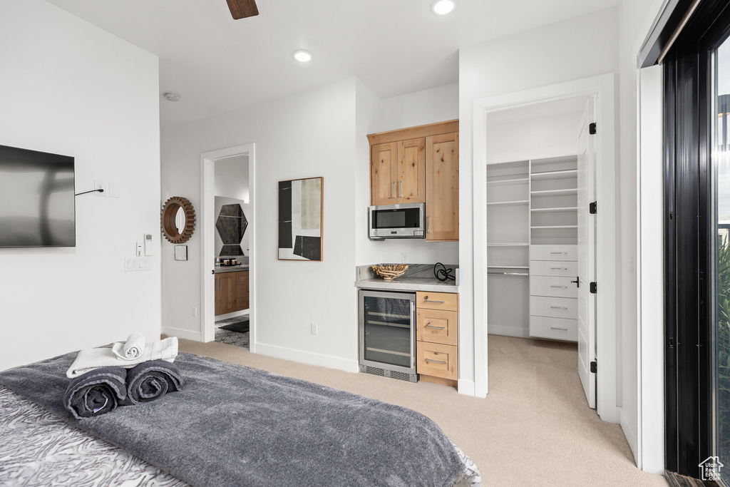 Bedroom featuring wine cooler, light colored carpet, a walk in closet, baseboards, and recessed lighting