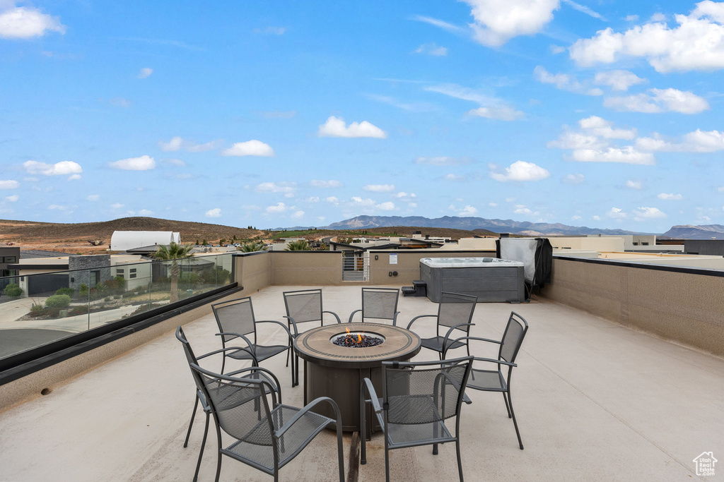 View of patio / terrace with an outdoor fire pit, a mountain view, and a covered hot tub