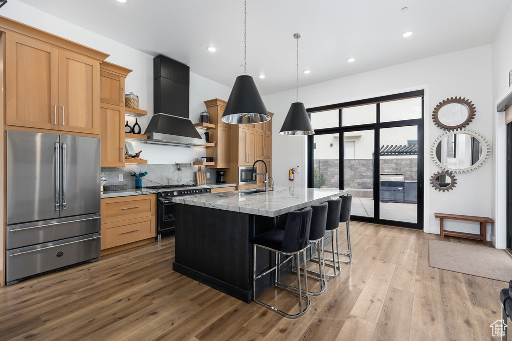 Kitchen featuring high quality appliances, premium range hood, open shelves, light wood-style floors, and recessed lighting