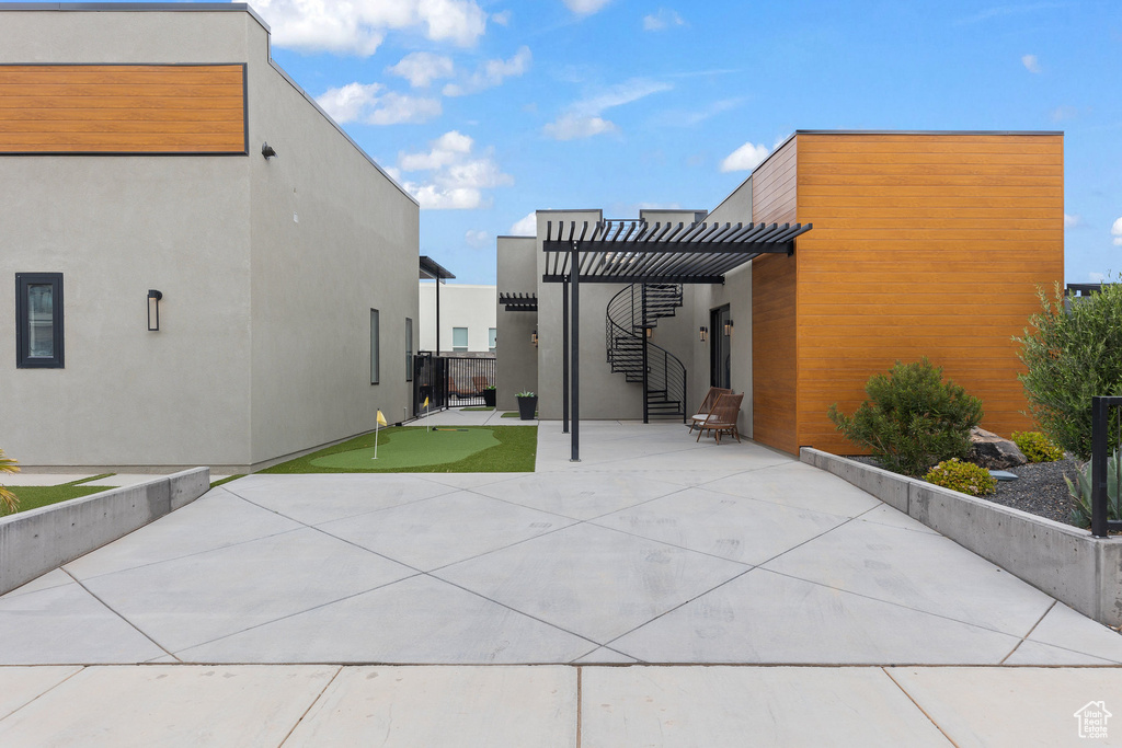 View of patio with a putting green and a pergola