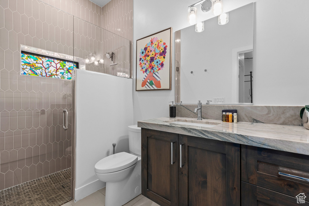 Full bathroom featuring tiled shower, toilet, vanity, and tile patterned floors