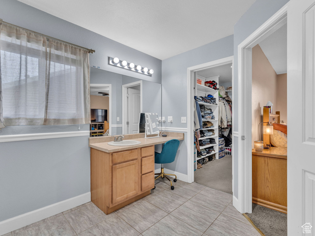 Bathroom with baseboards, a spacious closet, vanity, and tile patterned flooring
