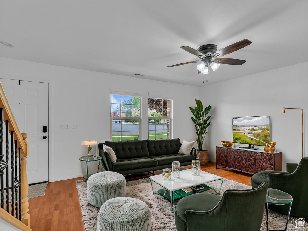Living room featuring stairs, wood finished floors, visible vents, ceiling fan, and baseboards