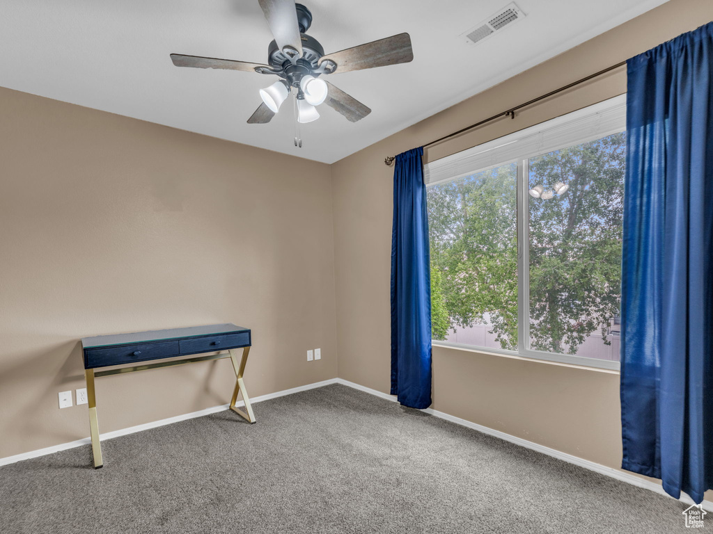 Carpeted spare room with baseboards, a ceiling fan, and visible vents