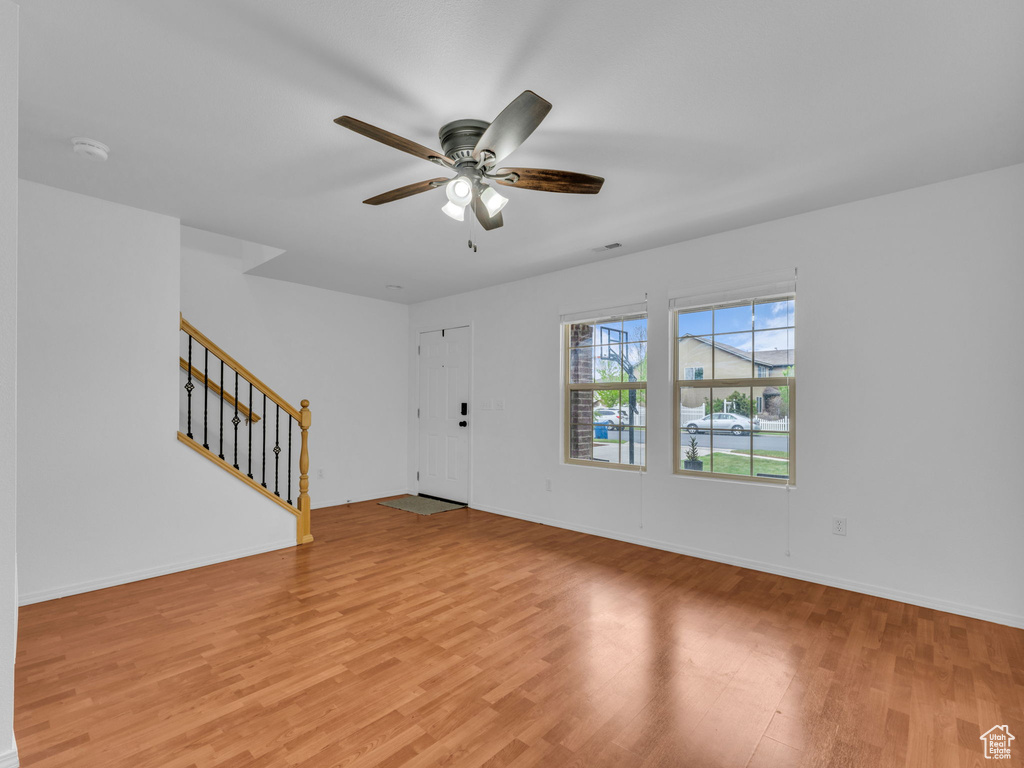Interior space featuring stairway, ceiling fan, light wood-style flooring, and baseboards