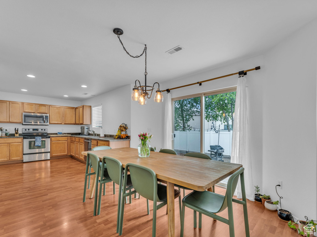 Dining area with light wood-type flooring, a wealth of natural light, an inviting chandelier, and recessed lighting